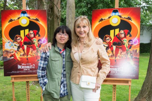 Two women posing next to posters of the incredibles.