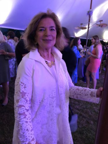 A woman in a white dress standing in front of a tent.