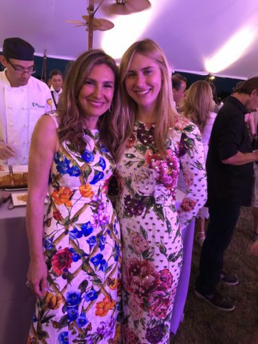 Two women in floral dresses standing next to each other at an event.
