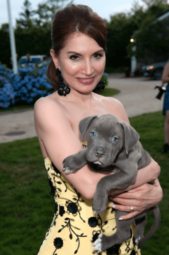A woman in a yellow dress holding a blue puppy.