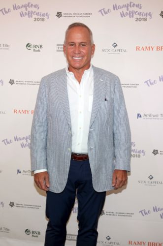 A man in a blue jacket standing on a red carpet.