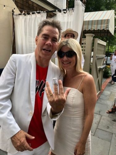 A man and woman posing for a picture with a wedding ring.