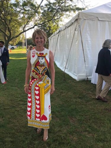A woman standing in front of a tent wearing a playing card dress.