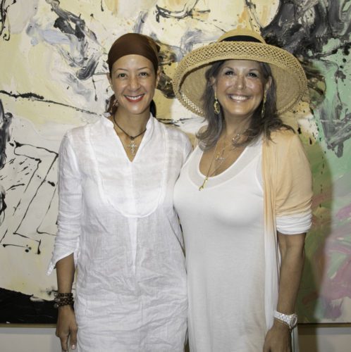 Two women standing in front of a painting.