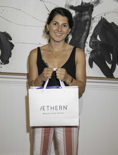 A woman holding a shopping bag in front of a painting.