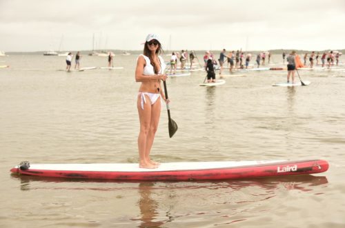 A woman standing on a paddle board in the water.