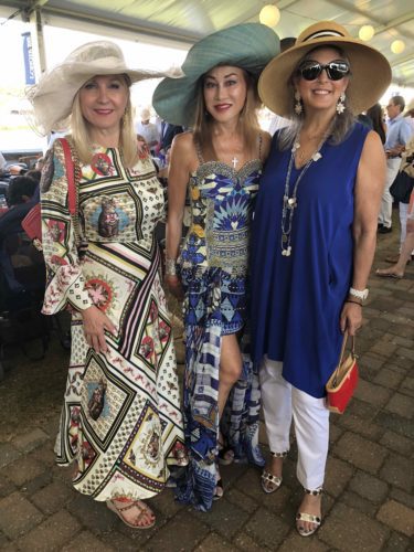 Three women posing for a photo at a horse race.