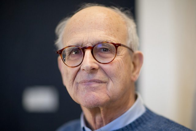 An older man wearing glasses and a sweater.