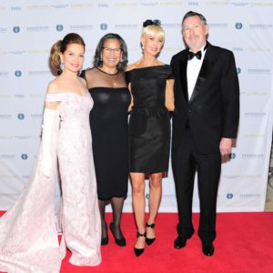 Four people posing for a picture on a red carpet.