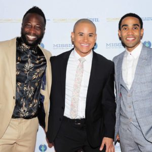 Three men in suits posing for a photo on a red carpet.