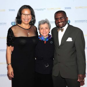 Three people posing for a photo on a red carpet.