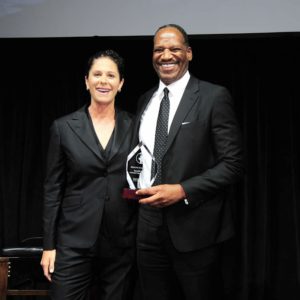 A man and woman standing next to each other holding an award.