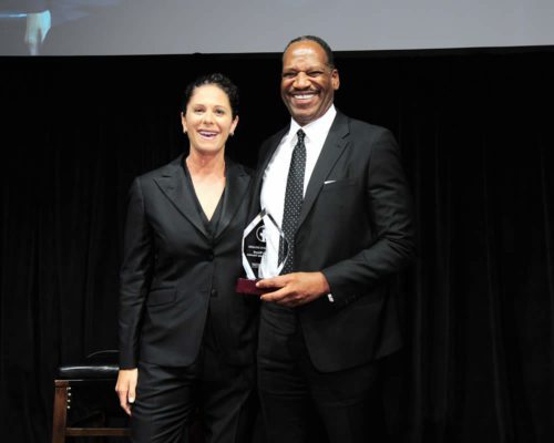 A man and woman standing next to each other holding an award.