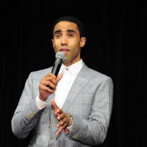 A man in a suit speaking into a microphone.