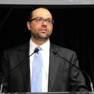 A man in a suit and tie standing at a podium.