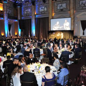 A large group of people sitting at tables in a large ballroom.