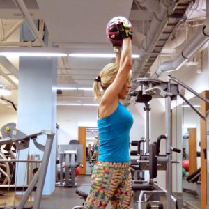 A woman lifting a ball in a gym.