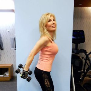 A woman holding a pair of dumbbells in a gym.