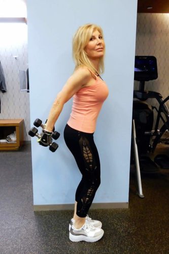 A woman holding a pair of dumbbells in a gym.