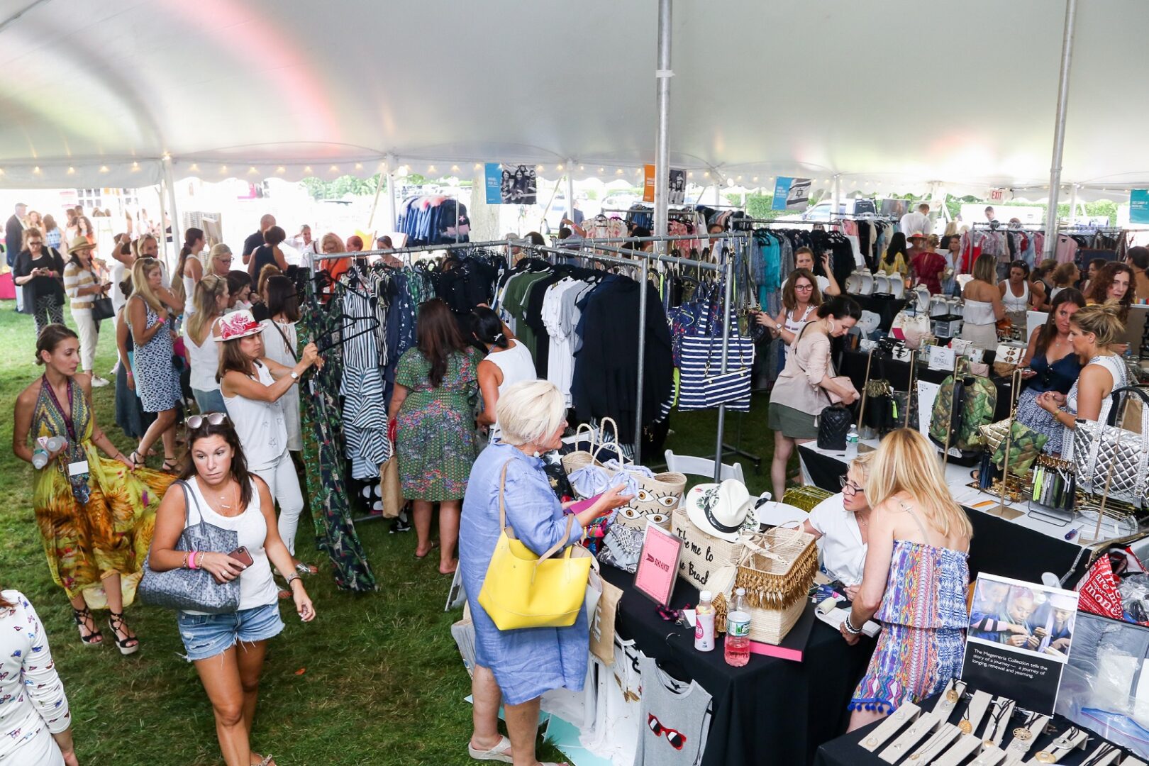 A crowd of people looking at clothes in a tent.