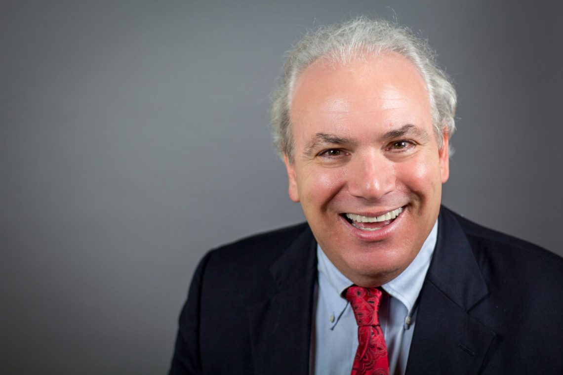 A smiling man in a suit and tie.