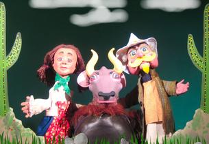 A group of puppets with a cow and cactus in the background.