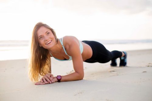 A woman doing push ups on the beach.
