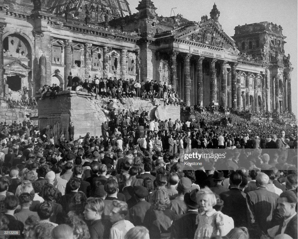 A crowd of people gathered in front of the reichstag building.