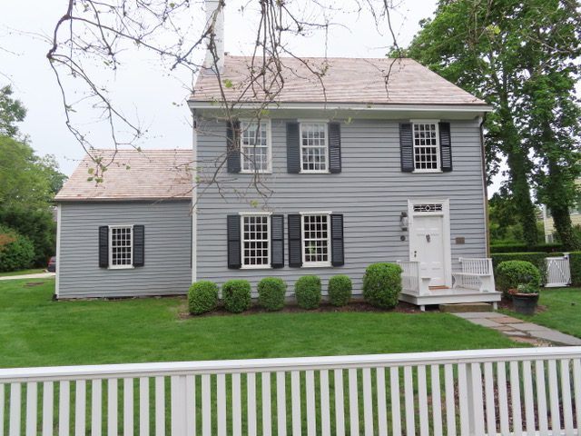 A gray house with a white picket fence.