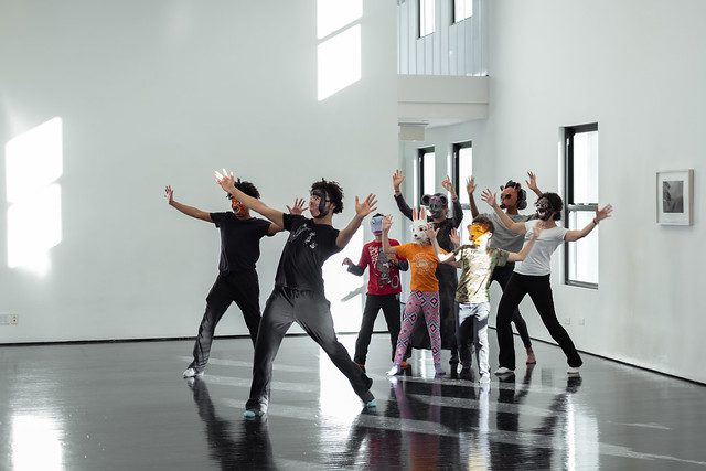 A group of people dancing in an empty room.