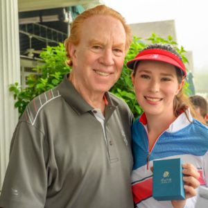 A man and woman posing for a photo with a golf ball.