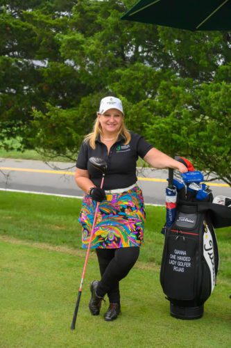 A woman posing with a golf bag.