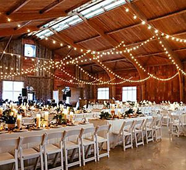 A large barn with tables and chairs set up for a wedding reception.