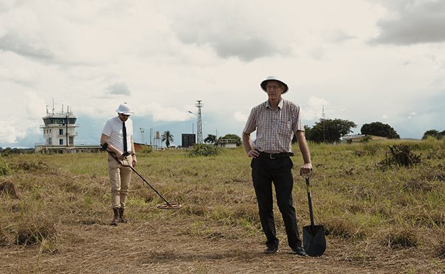 Two men standing in a field with shovels.