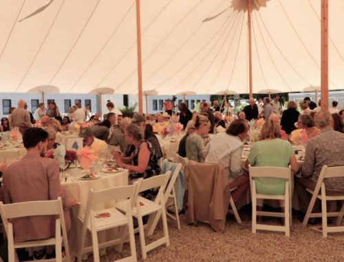 A group of people sitting at tables in a tent.