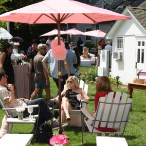 A group of people sitting under a pink umbrella.