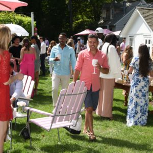 A group of people standing in a lawn with umbrellas.