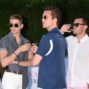 Three men standing next to each other at an outdoor event.