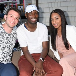 Three people posing for a picture on a couch.