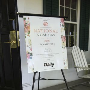 A sign that says national rose day in front of a door.