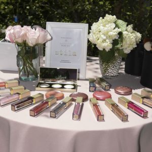 A table with makeup products and flowers on it.