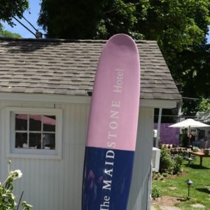 A blue and pink surfboard in front of a house.