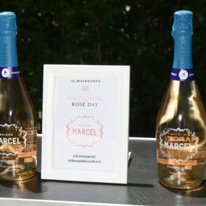 Two bottles of champagne sit on a table next to a sign.