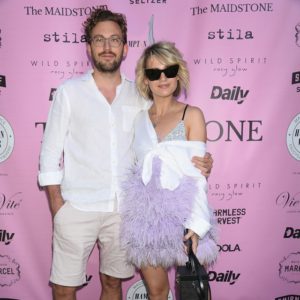 A man and woman standing next to each other on a pink carpet.