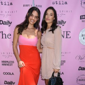 Two women posing for a picture on a pink carpet.