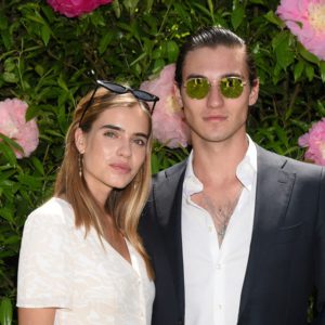 A man and woman posing for a photo in front of flowers.