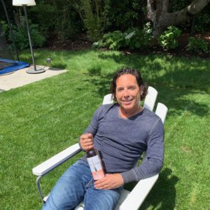 A man sitting in a lawn chair with a bottle of wine.