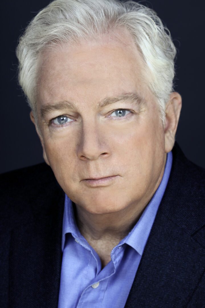 A man with white hair and blue eyes is posing for a photo.