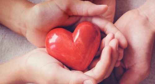 Close up shot of some hands holding a red color heart