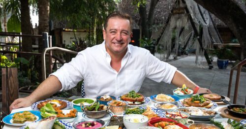 A man sitting in front of a table full of food.
